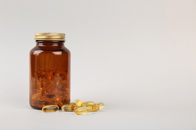 Photo of Jar with vitamin capsules on light grey background, space for text