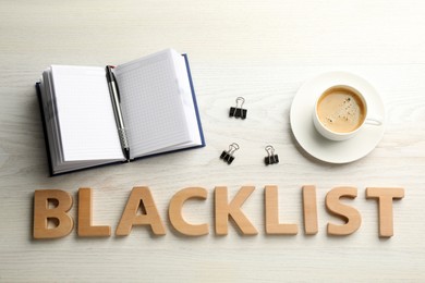 Word Blacklist of letters, cup with coffee and office stationery on white wooden desk, flat lay