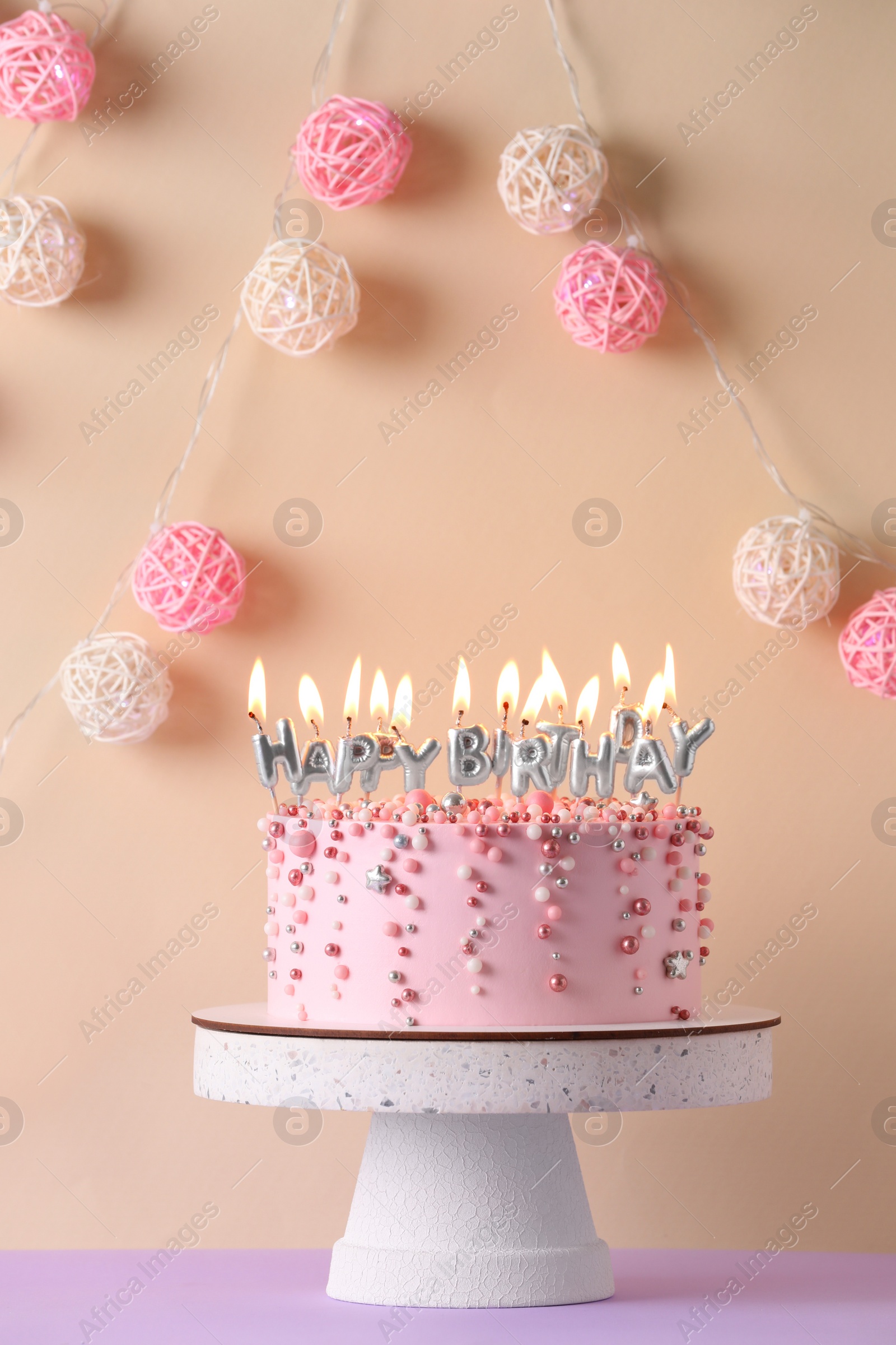 Photo of Birthday cake with burning candles on violet table