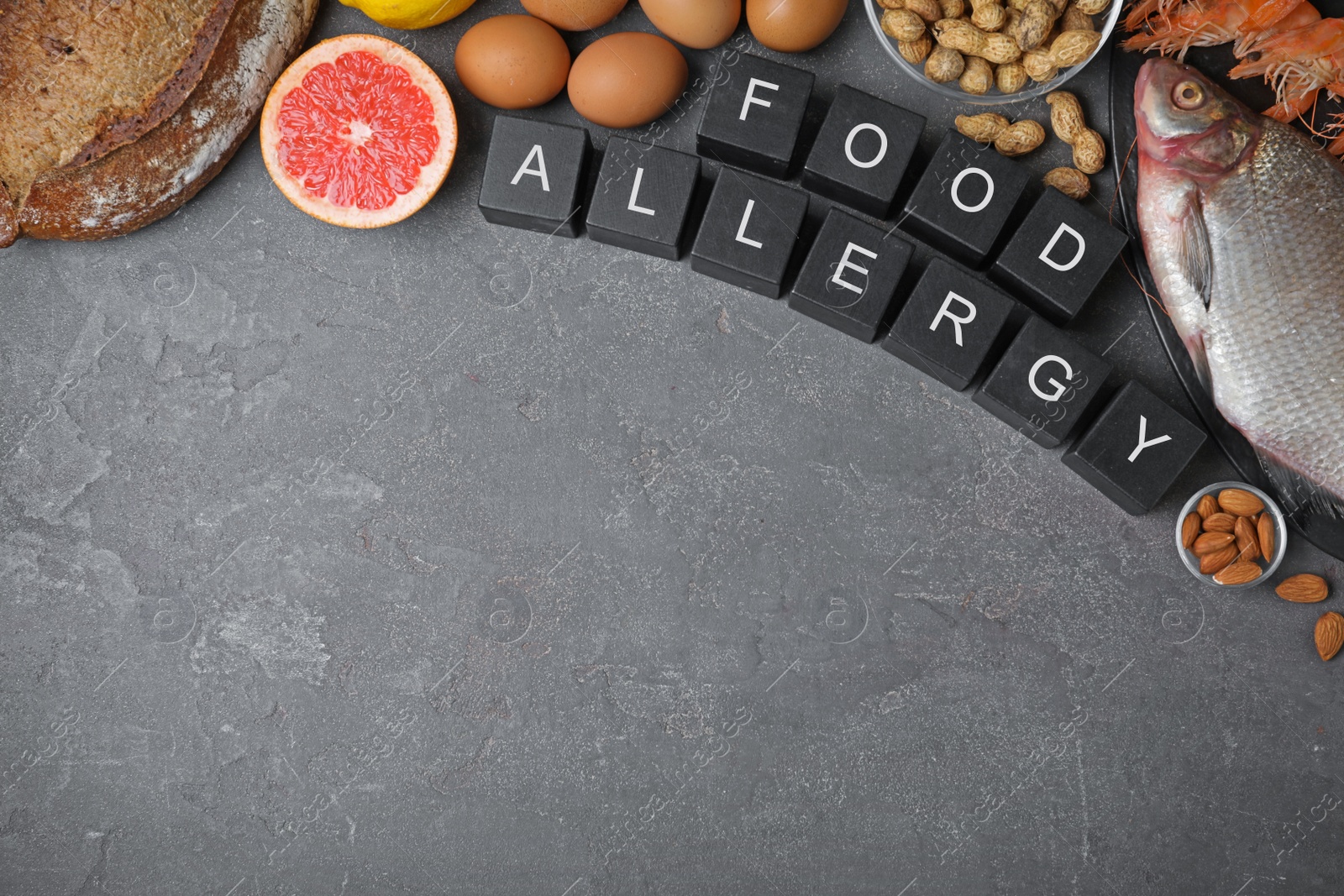 Photo of Flat lay composition of different products and black cubes with words Food Allergy on grey table, space for text