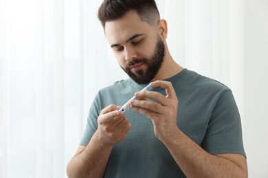 Diabetes test. Man checking blood sugar level with lancet pen at home