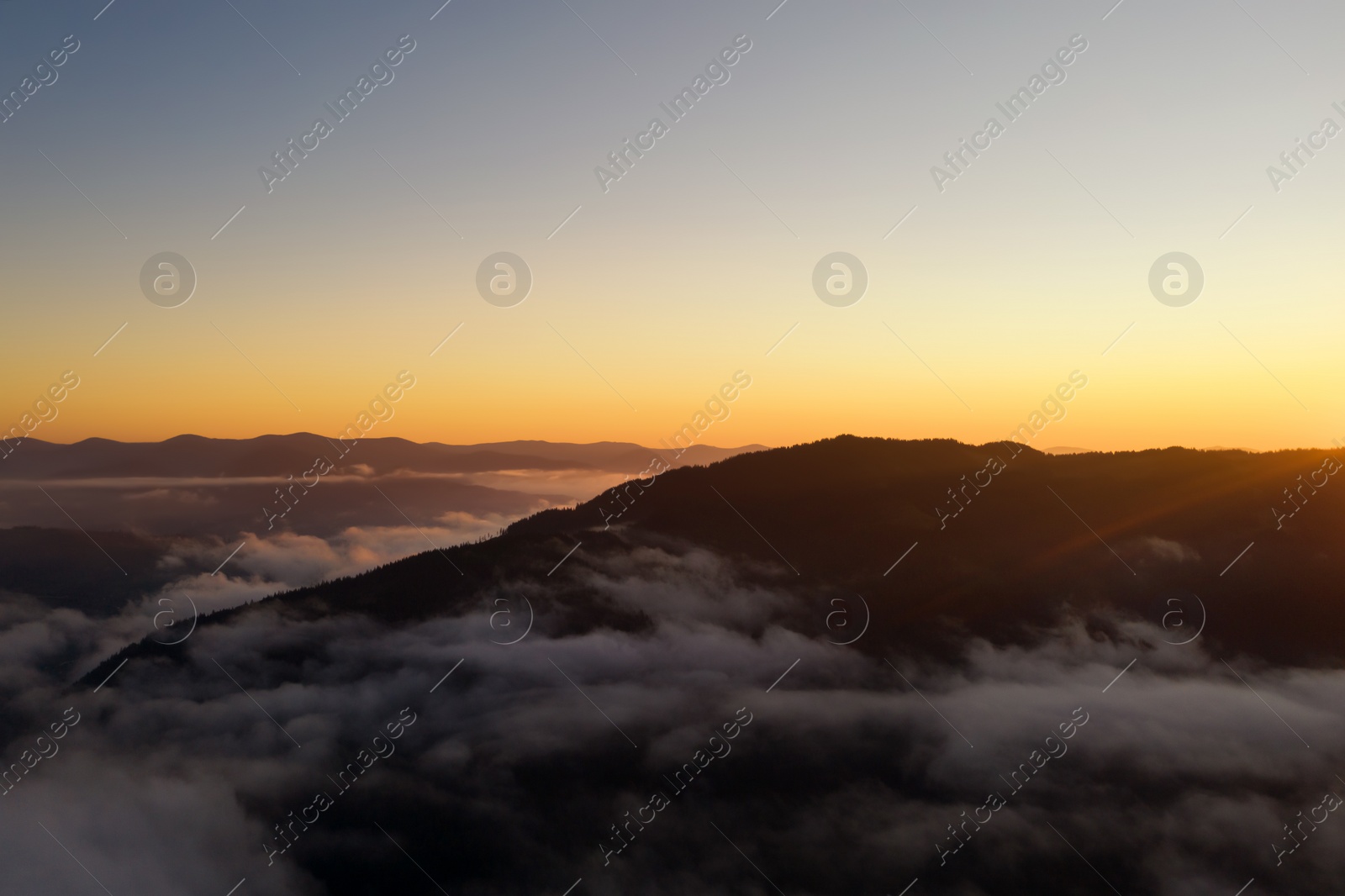 Image of Beautiful landscape with thick mist in mountains at sunset. Drone photography