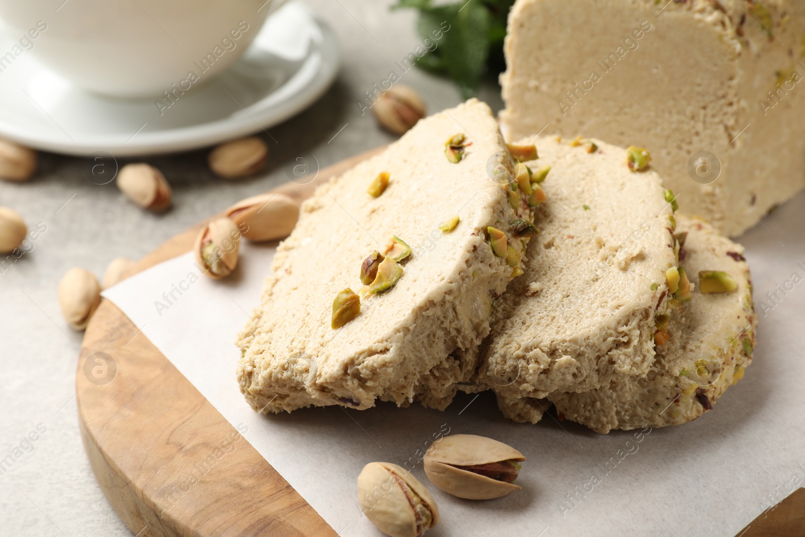 Photo of Tasty halva with pistachios on light grey table, closeup