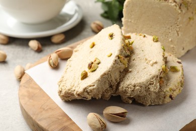 Photo of Tasty halva with pistachios on light grey table, closeup