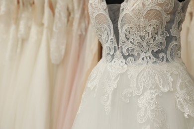 Photo of Beautiful wedding dress on mannequin in boutique, closeup