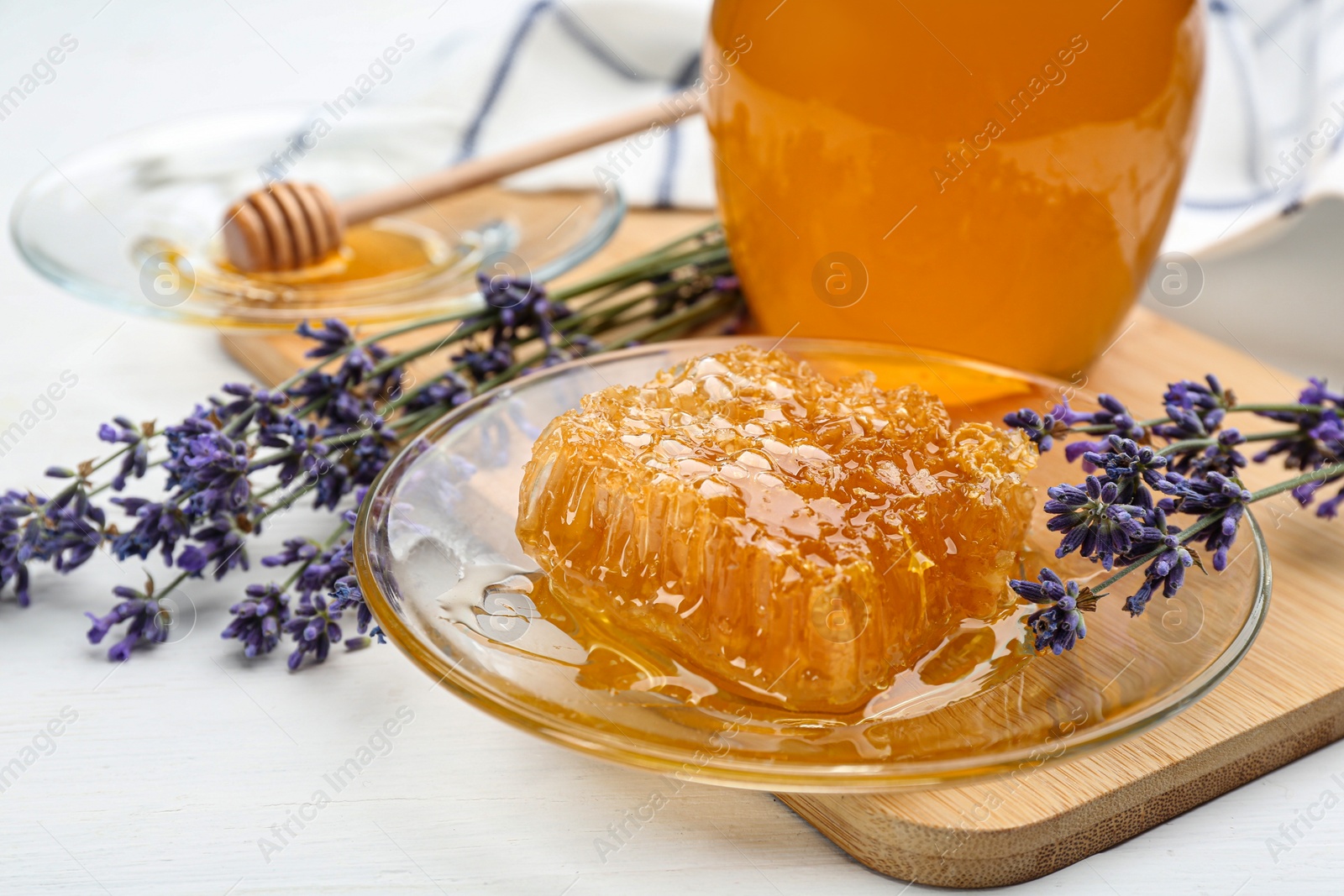 Photo of Tasty honey combs and lavender flowers on white wooden table, closeup