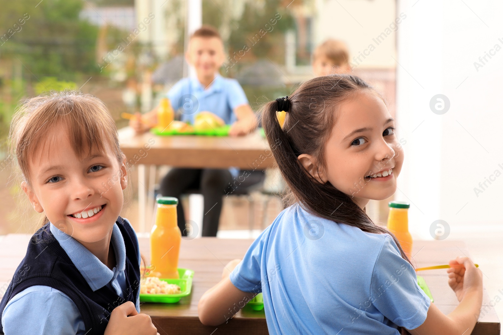 Photo of Happy girls at table with healthy food in school canteen