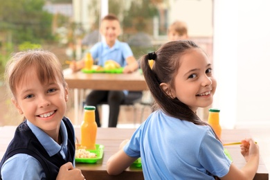 Photo of Happy girls at table with healthy food in school canteen