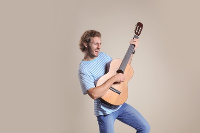 Photo of Young man playing acoustic guitar on grey background. Space for text