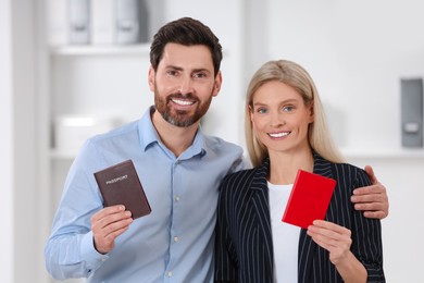Photo of Immigration. Happy man and woman with passports indoors