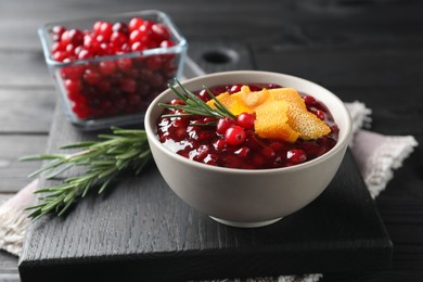 Photo of Fresh cranberry sauce, rosemary and orange peel in bowl on table, closeup