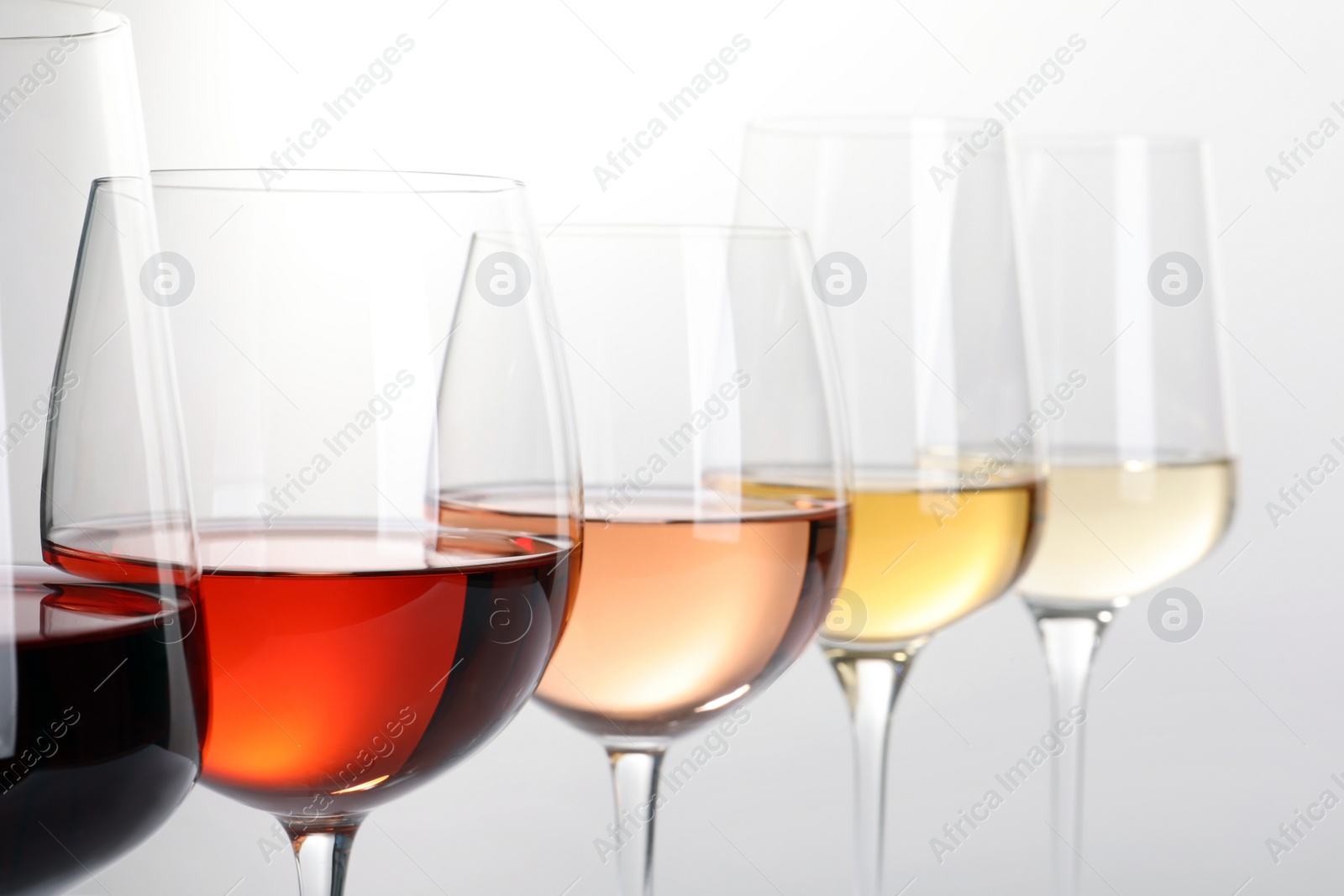 Photo of Row of glasses with different wines on white background