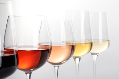 Row of glasses with different wines on white background