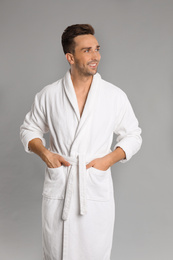 Happy young man in bathrobe on grey background