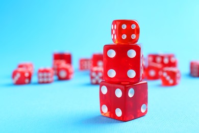 Many red game dices on light blue background, closeup