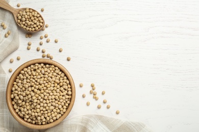 Soya beans with dishware on white wooden table, flat lay. Space for text