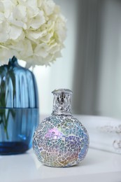 Photo of Stylish catalytic lamp with beautiful bouquet on white table. Cozy interior