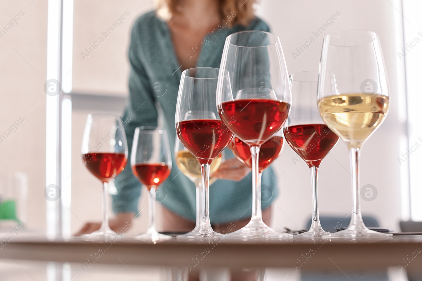 Photo of Glasses with delicious wine and blurred woman on background