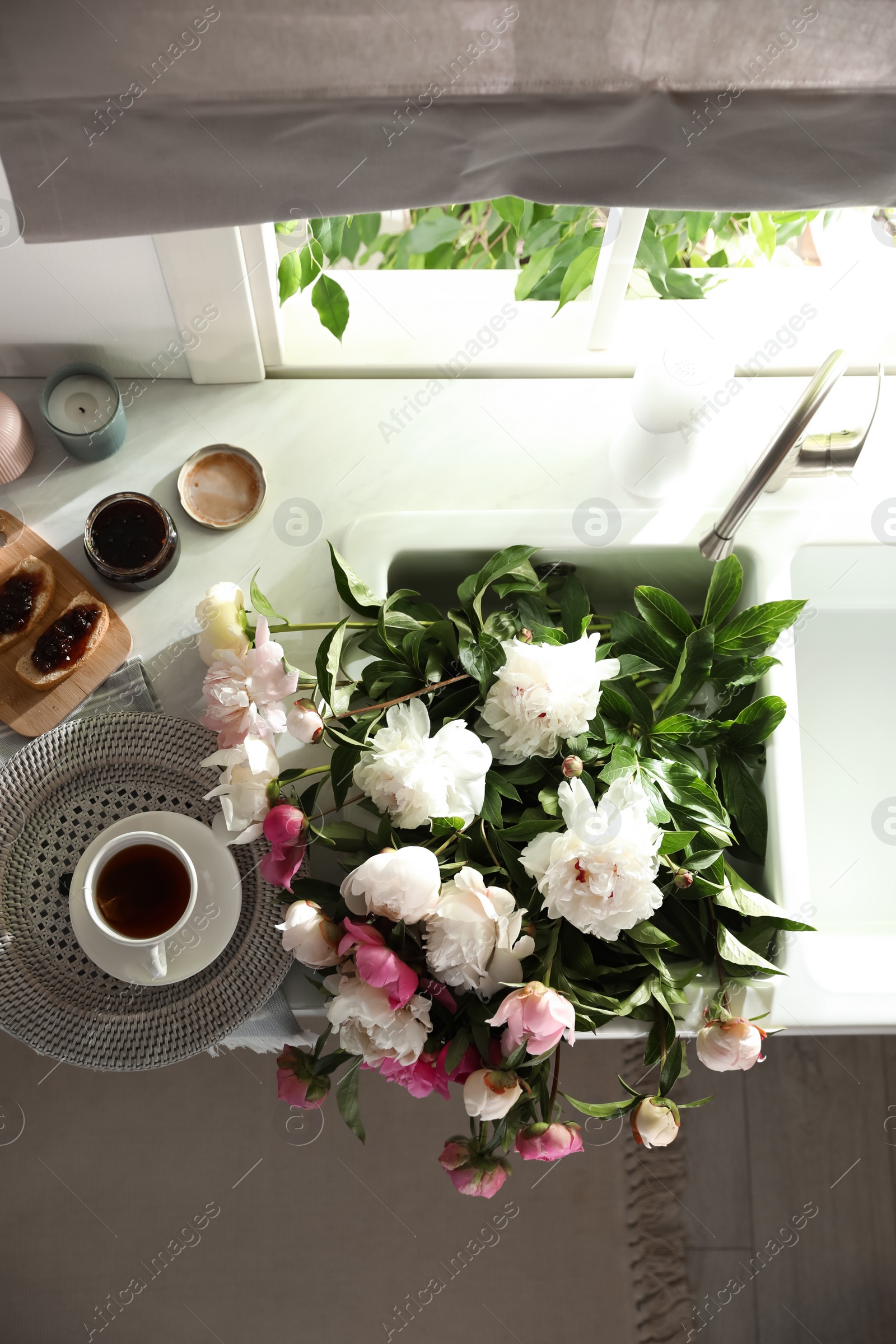 Photo of Beautiful peonies and breakfast on kitchen counter, flat lay