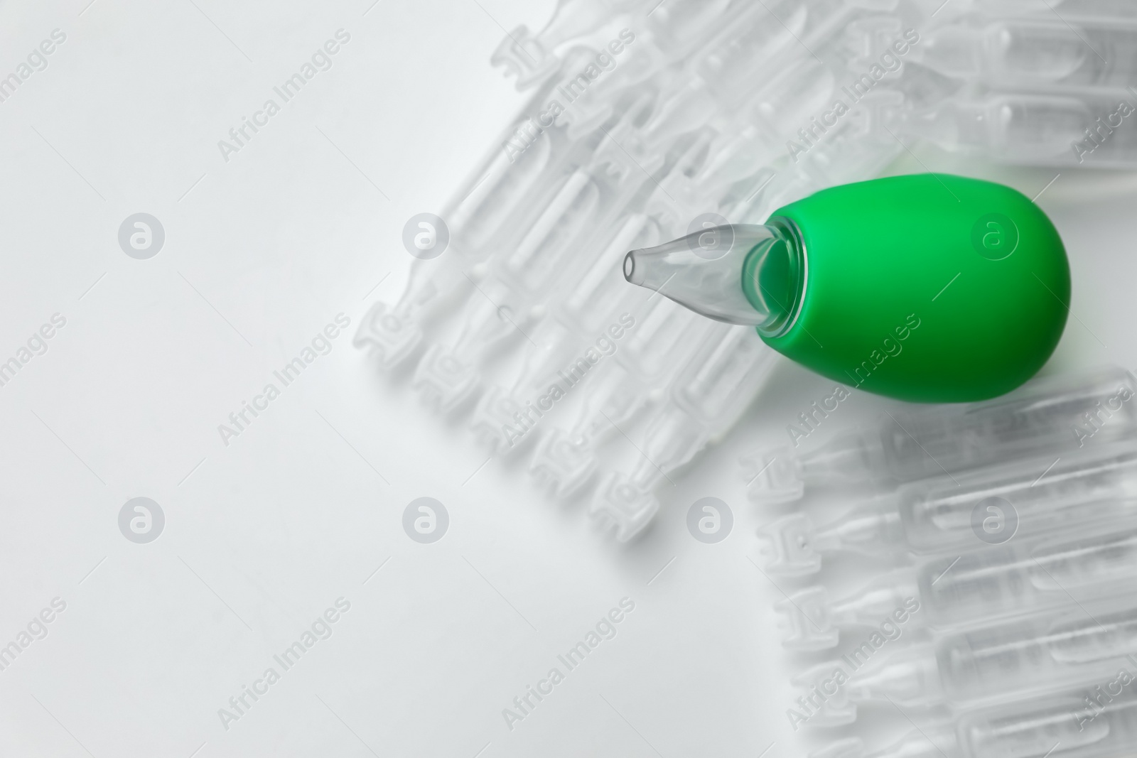 Photo of Single dose ampoules of sterile isotonic sea water solution and nasal aspirator on white background, above view. Space for text