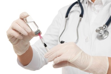 Doctor filling syringe with medication from glass vial on white background, closeup