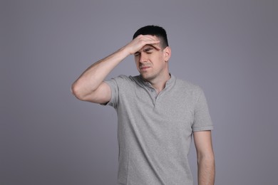 Photo of Young man suffering from headache on grey background. Cold symptoms