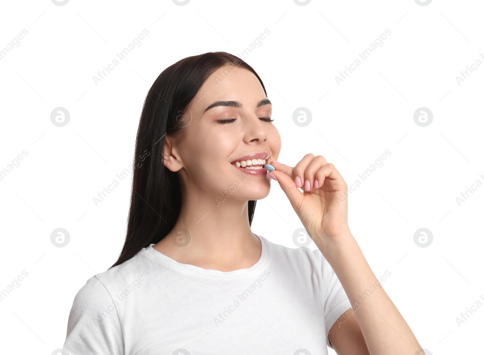 Photo of Young woman taking vitamin pill on white background