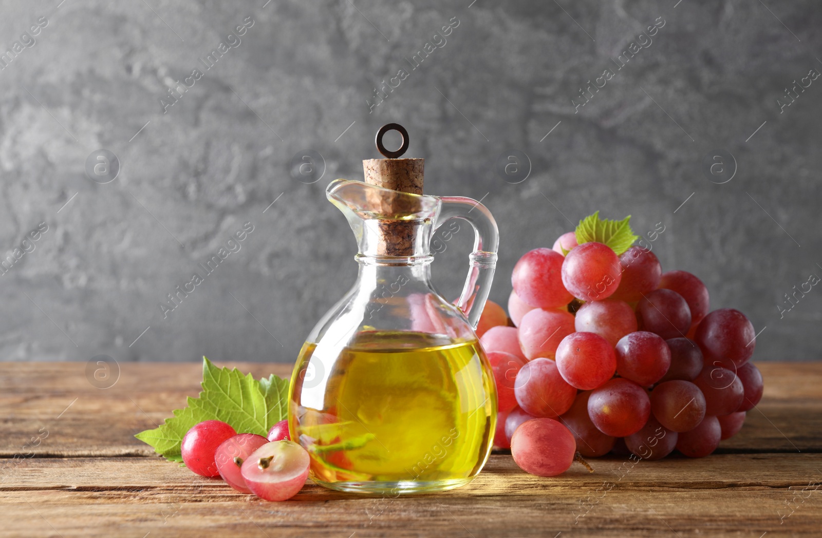 Photo of Jug of natural grape seed oil on wooden table. Organic cosmetic