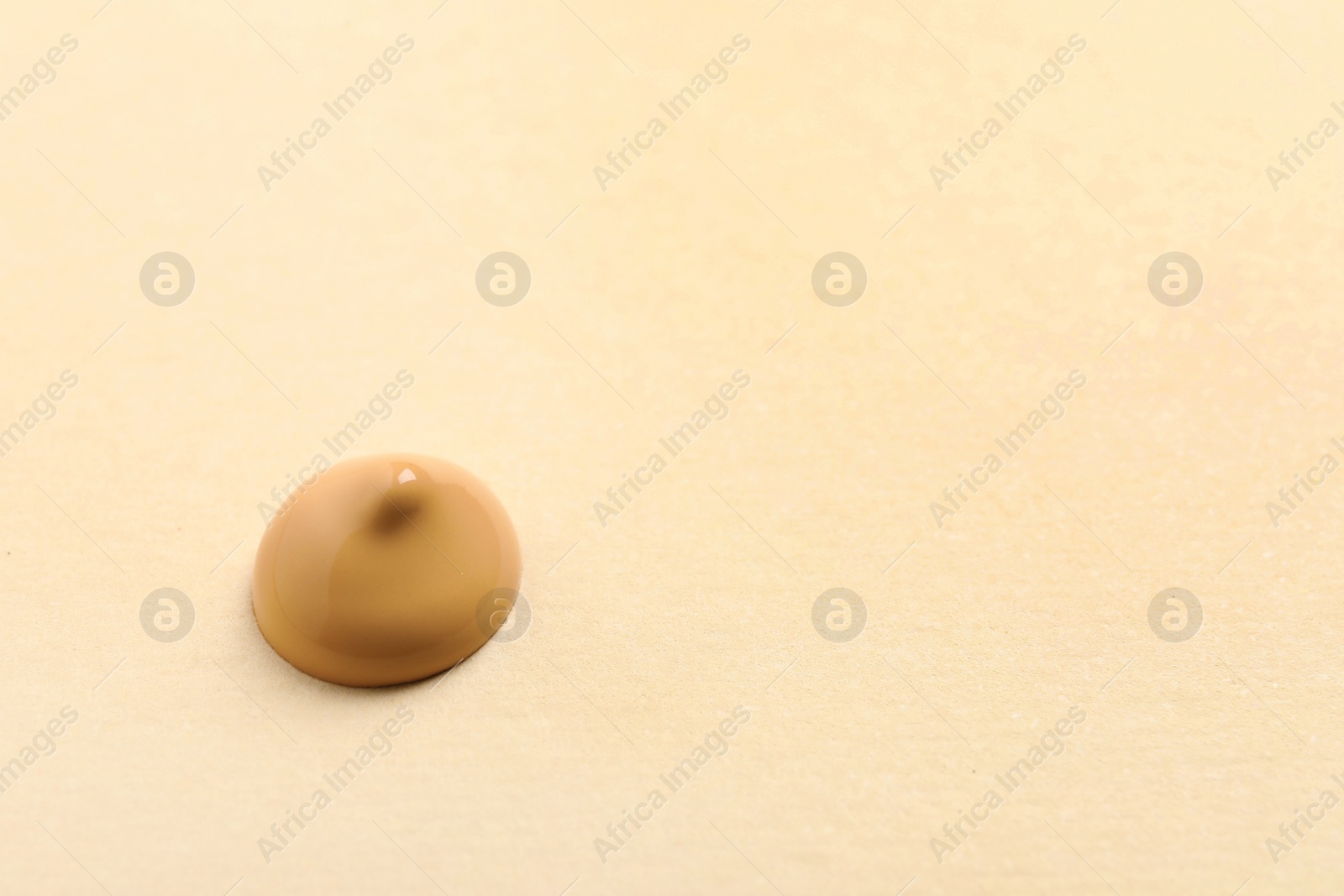 Photo of Drop of skin foundation on beige background. Space for text