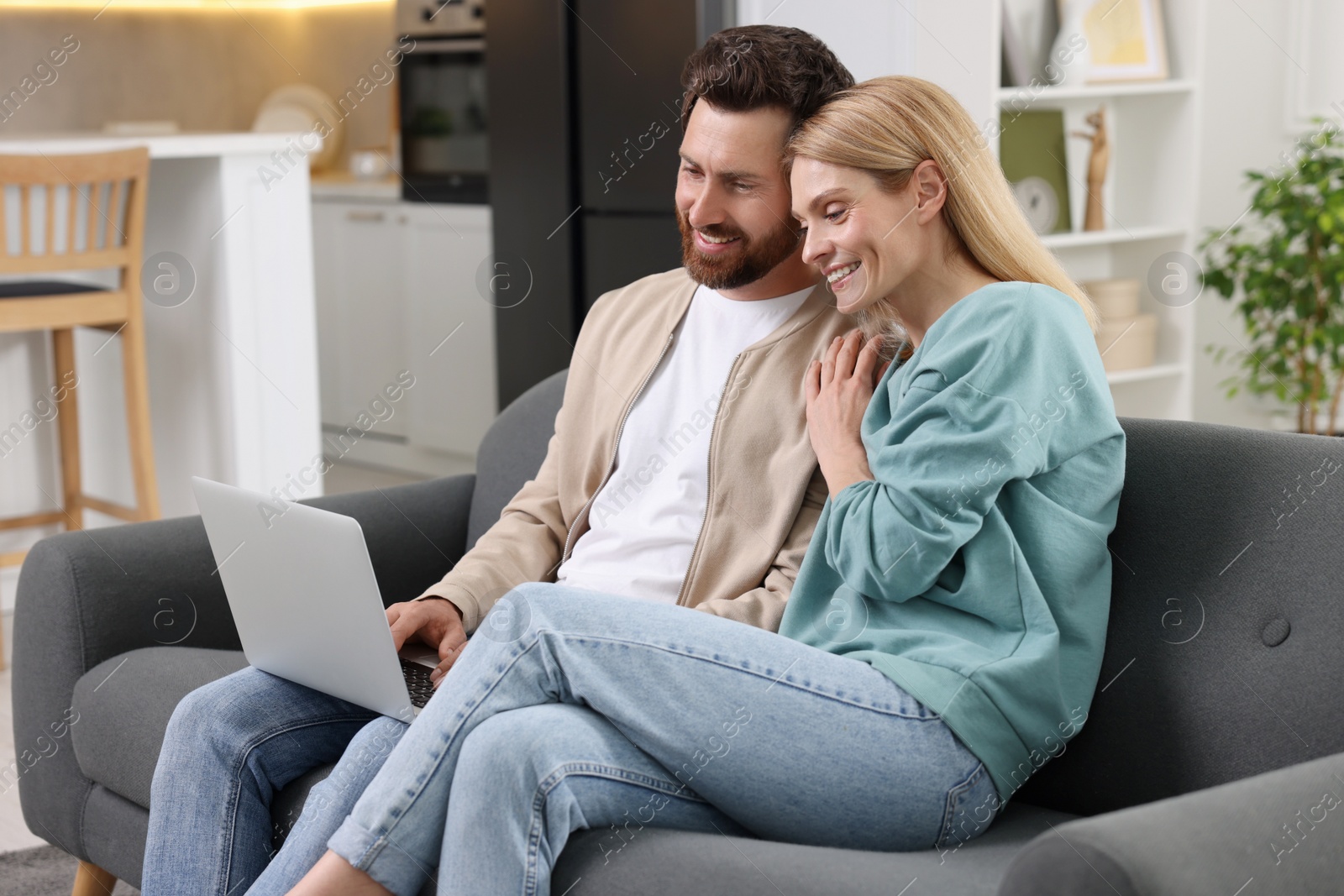 Photo of Happy couple with laptop on sofa at home