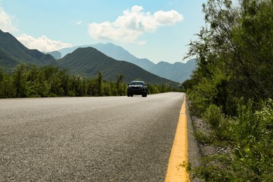 Picturesque view of road with car, mountains and plants outdoors