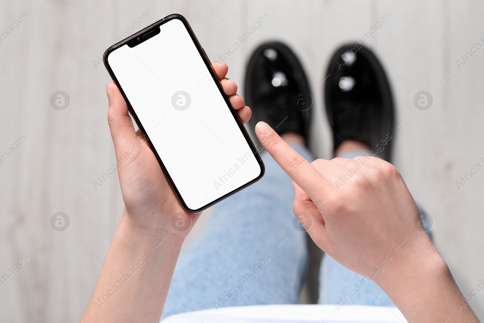 Photo of Woman holding smartphone with blank screen indoors, top view. Mockup for design