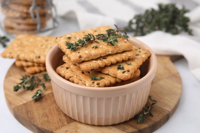 Photo of Cereal crackers with flax, sesame seeds and thyme in bowl on light table, closeup