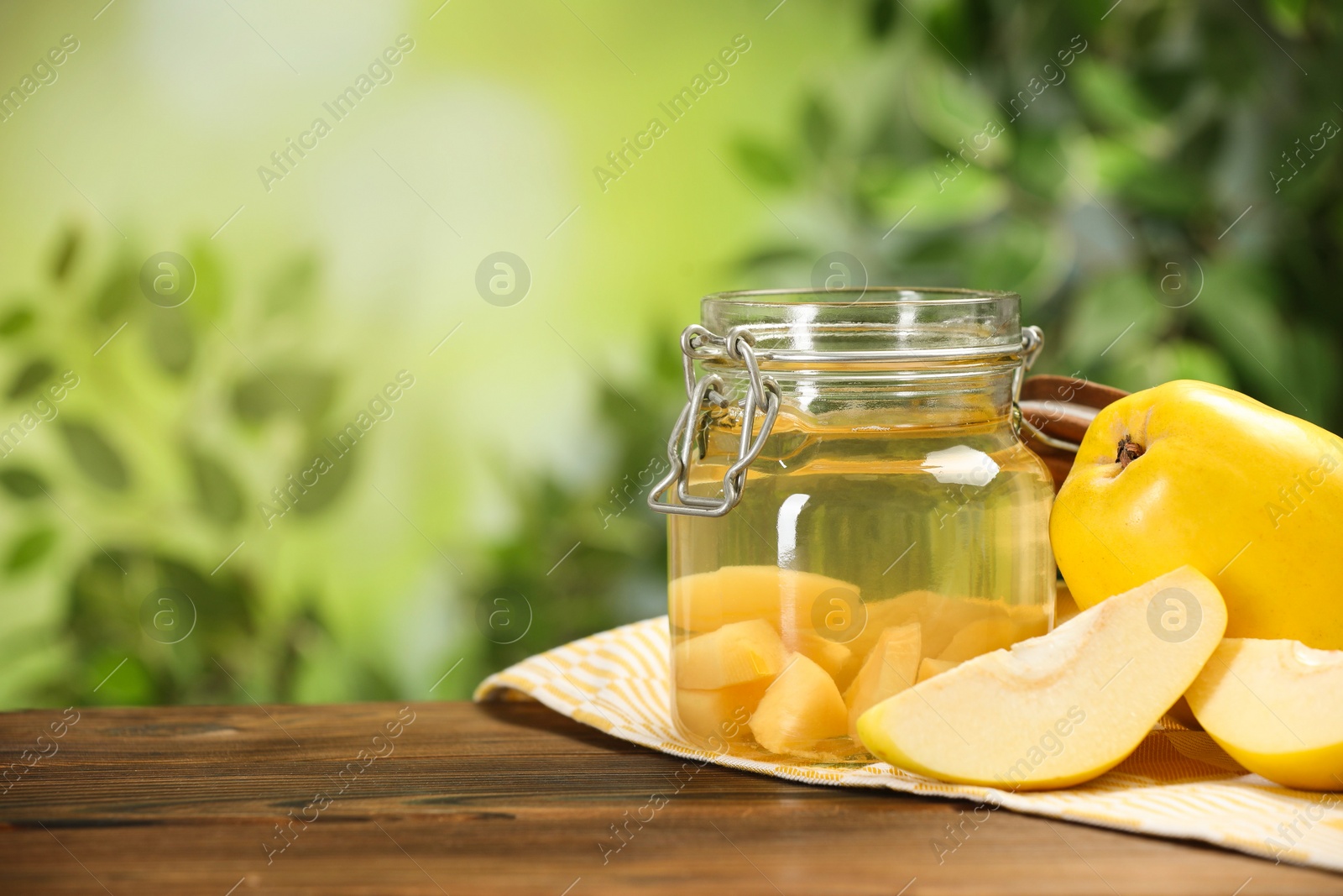 Photo of Delicious quince drink and fresh fruits on wooden table against blurred background. Space for text