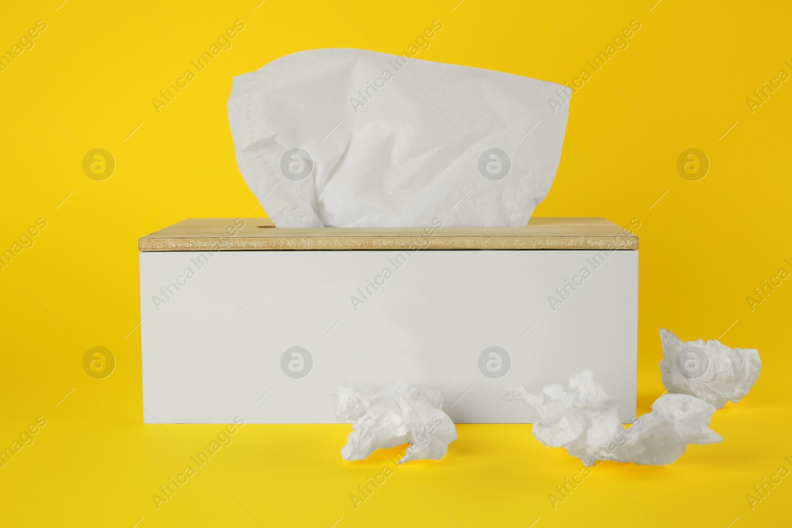 Photo of Used paper tissues and holder on yellow background