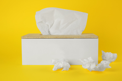 Photo of Used paper tissues and holder on yellow background