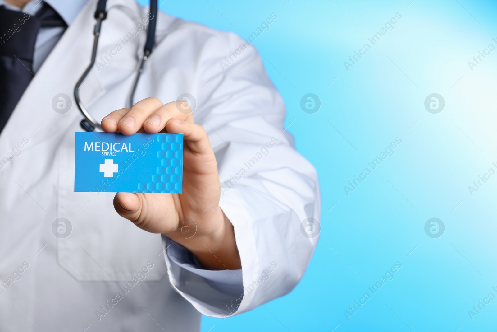 Photo of Doctor holding business card on color background, closeup with space for text. Medical service