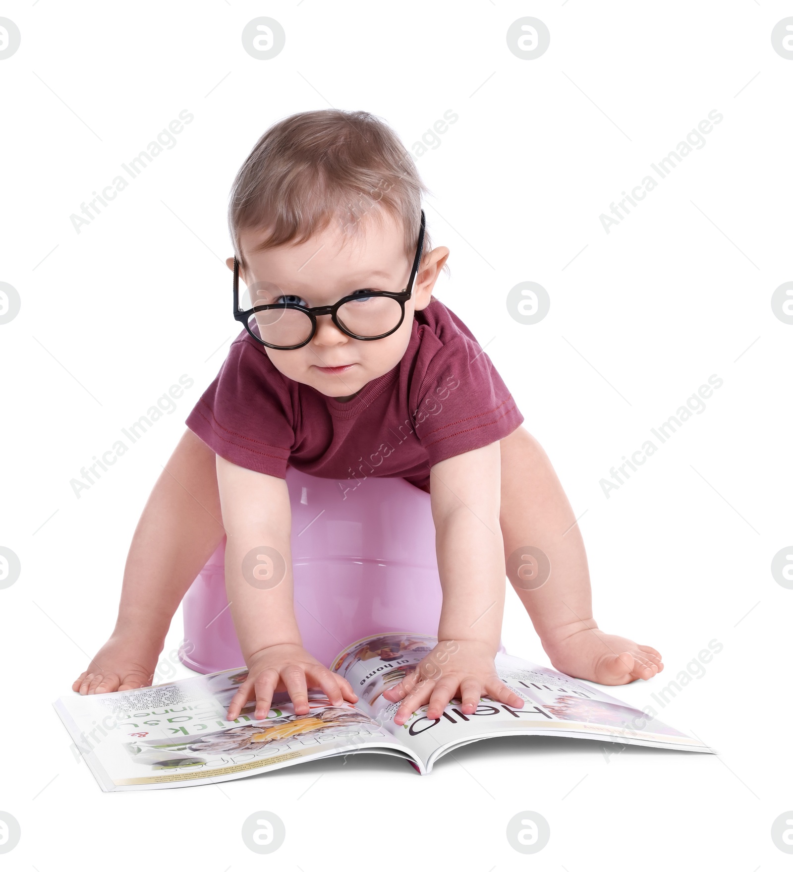 Photo of Little child with glasses and book sitting on baby potty against white background