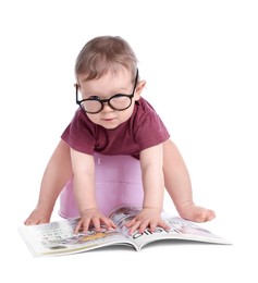 Little child with glasses and book sitting on baby potty against white background