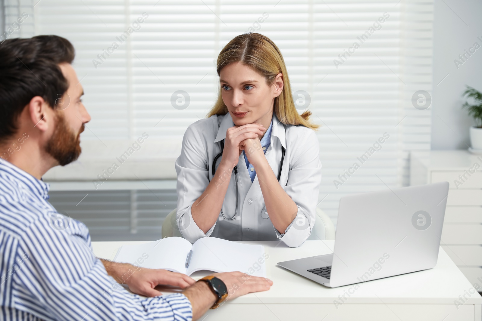 Photo of Doctor consulting patient at white table in clinic