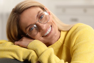 Photo of Happy woman in stylish glasses on sofa indoors