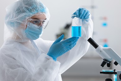 Photo of Young scientist holding beaker with sample in laboratory