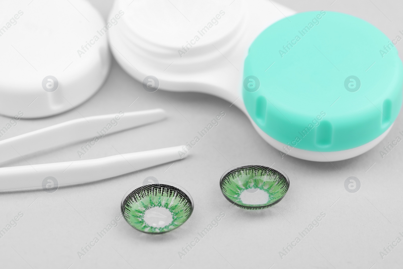 Photo of Green contact lenses, case and tweezers on white background