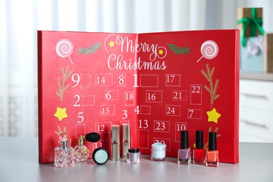 Photo of Advent calendar with different cosmetics and perfumes on light grey table. Presents for Christmas