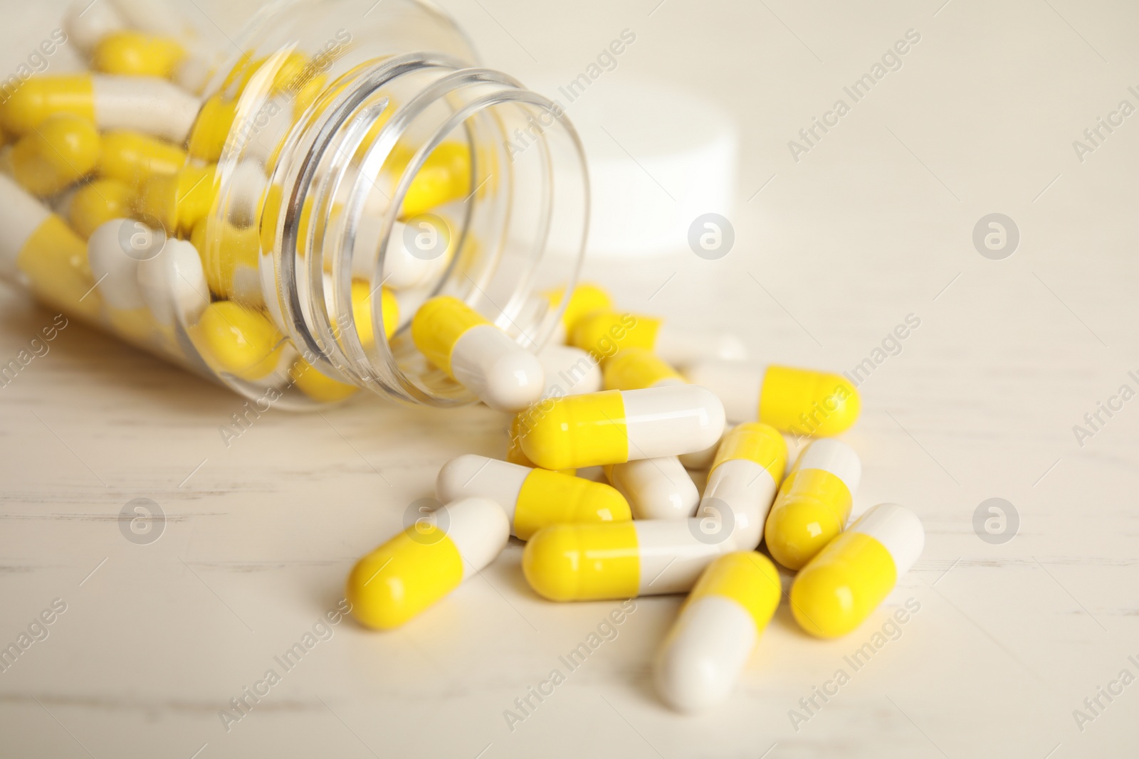 Photo of Bottle with vitamin pills on light table, closeup