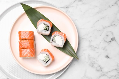 Tasty sushi rolls with green leaf on white marble table, top view