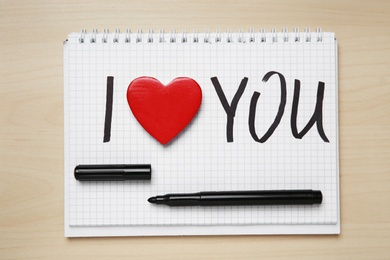 Photo of Notebook with written text I LOVE YOU and marker on wooden background, top view