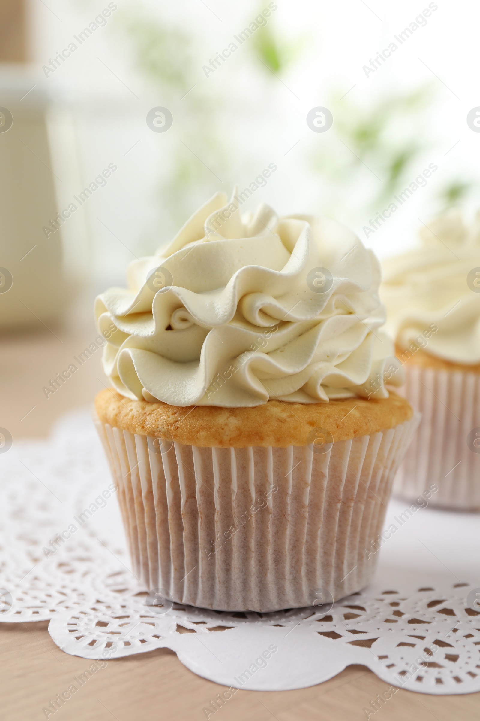 Photo of Tasty cupcakes with vanilla cream on light wooden table, closeup