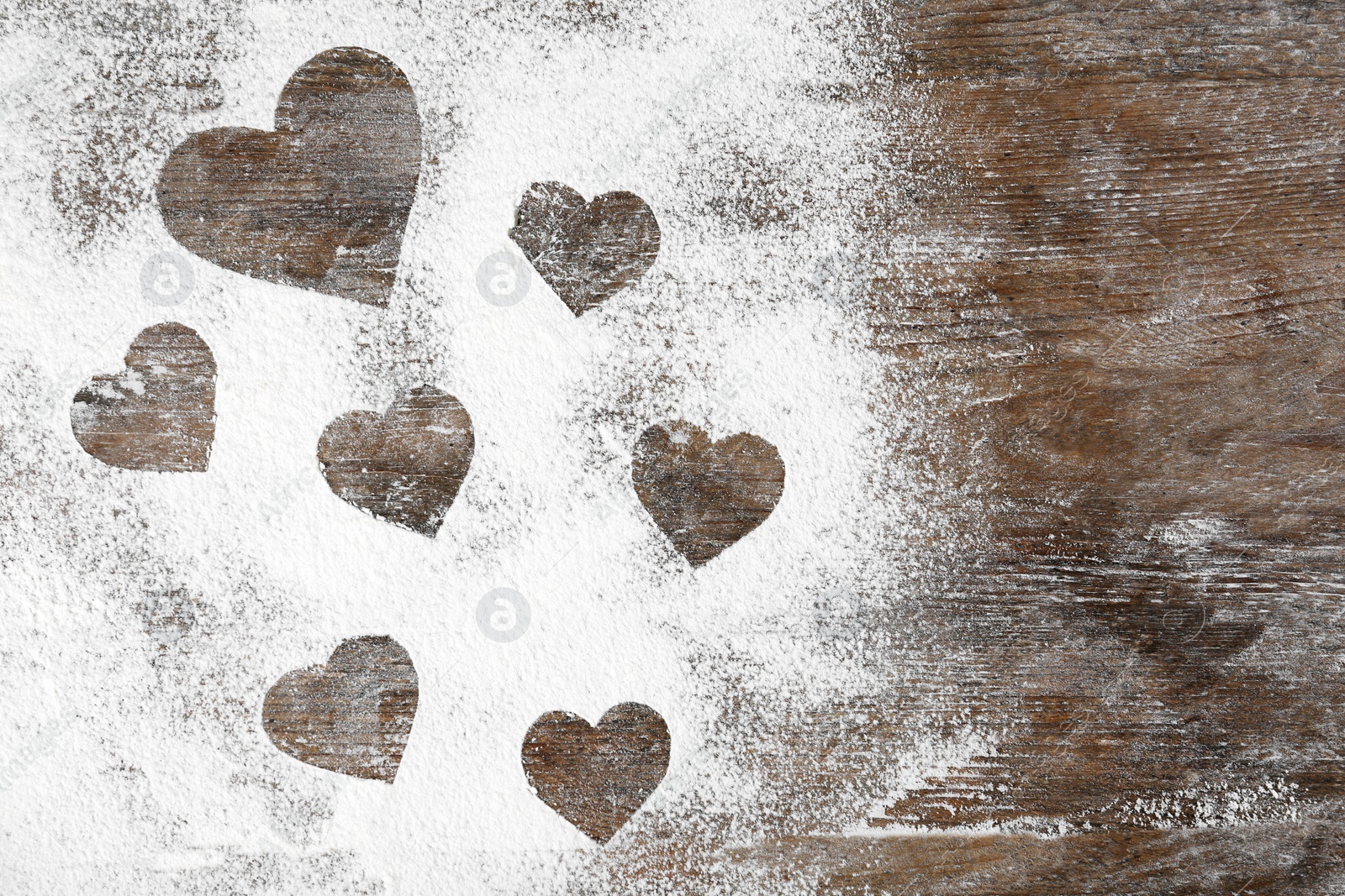 Photo of Heart shapes made of flour on wooden table, top view. Space for text
