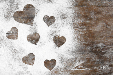 Heart shapes made of flour on wooden table, top view. Space for text